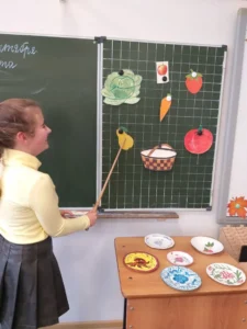 Ученица показывает фрукты и овощи
