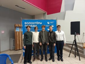Ребята на фоне стенда "Волонтёры победы"